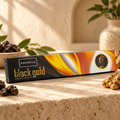 Nandita Black Gold 15g incense on a warm ivory stone surface with resin and gold accents